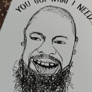 May include: A black and white line drawing of a smiling person with a beard. The text "YOU GOT WHAT I NEED..." is above the person's head. The drawing is on a white card.