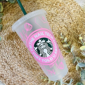 Könnte beinhalten: Ein durchsichtiger wiederverwendbarer Becher aus Plastik mit einem rosafarbenen Design, das den Text "I'm the nail tech they told you about" und ein stilisiertes grünes Starbucks-Logo zeigt. Der Becher hat einen grünen Strohhalm.