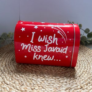 May include: Red metal tin with a white inscription that reads "I wish Miss Javaid knew..." with white stars and shooting stars on the tin.