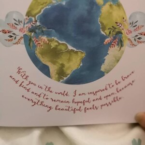 May include: A watercolor illustration of the Earth with a quote about being inspired to be brave and kind. The quote reads, "With you in the world, I am inspired to be brave and kind and to remain hopeful and open, because everything beautiful feels possible."