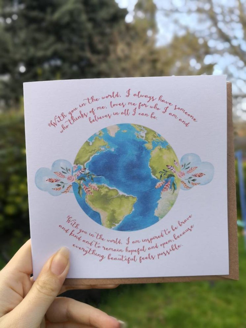 May include: A card with a watercolor illustration of the Earth with pink hearts and floral accents. The text reads "With you in the world. I always have someone who thinks of me, loves me for who I am and believes in all I can be. With you in the world. I am inspired to be brave and kind and to remain hopeful and open, because everything beautiful feels possible."