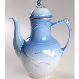 May include: A blue and white porcelain coffee pot with a gold trim and a lid. The pot features a design of two seagulls in flight.