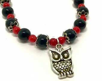 May include: Black and red beaded bracelet with a silver owl charm.