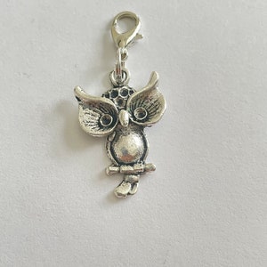 May include: A silver owl charm with a lobster clasp. The owl is perched on a branch, with detailed feather and eye features. Suitable for jewellery making, keychains, or other craft projects.