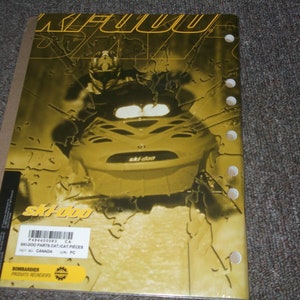 Pu&ograve; includere: Un catalogo di ricambi per motoslitta Ski-Doo giallo e nero con un'immagine ravvicinata di una motoslitta Ski-Doo sulla copertina. Il catalogo &egrave; intitolato "SK-000 PARTS CAT/CAT PIECES" e ha il numero P484400063 stampato sulla copertina.