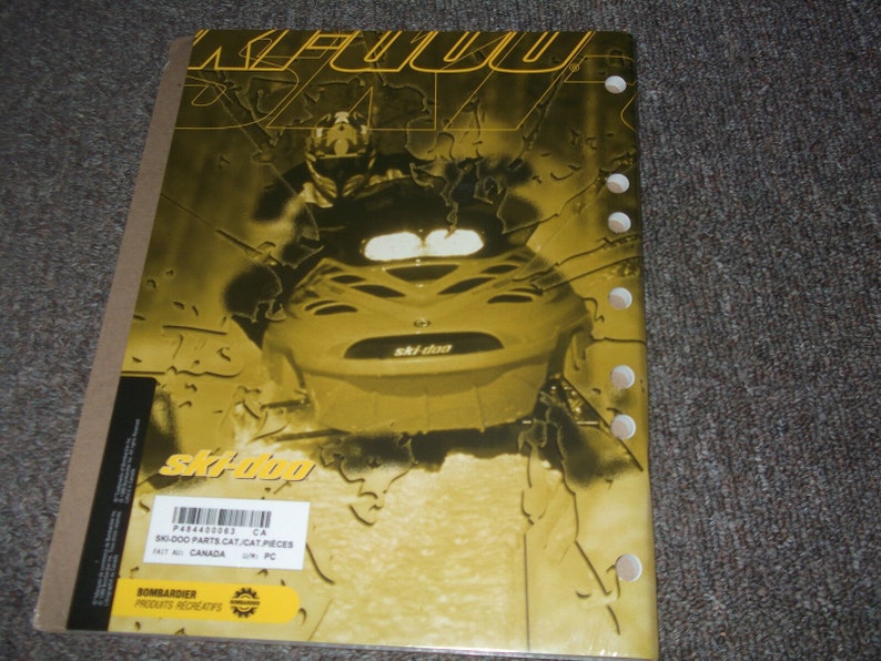 Pu&ograve; includere: Un catalogo di ricambi per motoslitta Ski-Doo giallo e nero con un'immagine ravvicinata di una motoslitta Ski-Doo sulla copertina. Il catalogo &egrave; intitolato "SK-000 PARTS CAT/CAT PIECES" e ha il numero P484400063 stampato sulla copertina.