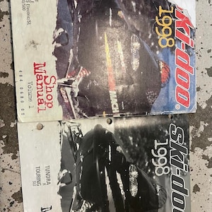 May include: Two shop manuals for 1998 Ski-Doo snowmobiles. The top manual is titled "Shop Manual, Volume 1" and lists the models Tundra II LT, Touring E/LE, Formula S/S Electric/SL, and Skandic 380/500. The bottom manual is titled "Shop Manual, Supplement" and lists the model Tundra R Touring SLE.