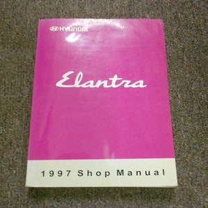 Puede incluir: Un manual de taller Hyundai Elantra 1997 de color rosa. La portada presenta el logotipo de Hyundai y el nombre del modelo en blanco.