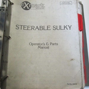 May include: A white binder with the title "STEERABLE SULKY Operator's & Parts Manual" and the Exmark logo. The binder has a red tab labeled "Steering System".