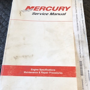 Könnte beinhalten: Ein weißes Mercury-Servicehandbuch für 115/135/150/175 Optimax-Motoren mit Direkteinspritzung. Das Handbuch behandelt Motorspezifikationen, Wartung und Reparaturverfahren. Der Einband hat einen roten Streifen mit den Worten "Motorspezifikationen" und "Wartungs- und Reparaturverfahren", die in Schwarz gedruckt sind.