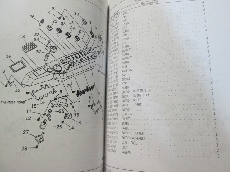May include: A black and white diagram of a car dashboard with numbered parts labeled with their corresponding names. The diagram includes a variety of switches, buttons, and other components. The diagram is labeled "Fig. K0210-10A0".