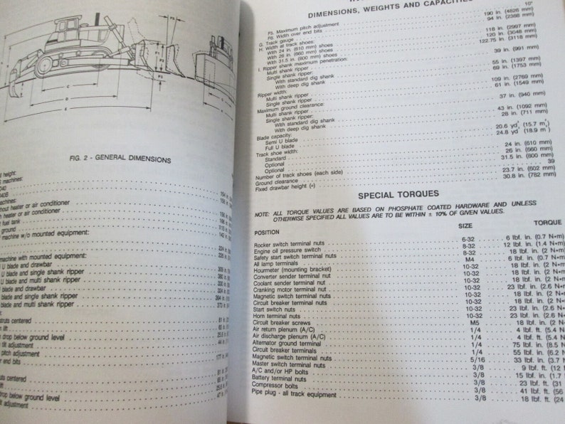 May include: A black and white technical manual with a diagram of a bulldozer and a table of dimensions, weights, and capacities. The table lists measurements in inches and millimeters. The manual also includes a section on special torques with a table listing torque values for various sizes of bolts and screws.