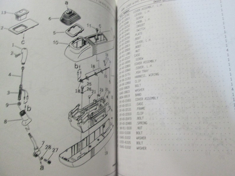 May include: A black and white diagram showing the parts of a car's gear shift assembly. The diagram includes numbers and letters to identify each part. The parts are labeled with their names, such as "lever assembly", "screw", "switch", "plate", "lever", "case", "screw", "cover assembly", "ashtray", "harness, wiring", "clip", "washer", "band", "cover assembly", "cage", "frame", "clip", "bolt", "spring", "nut", "bolt", "washer", "bolt", "washer".