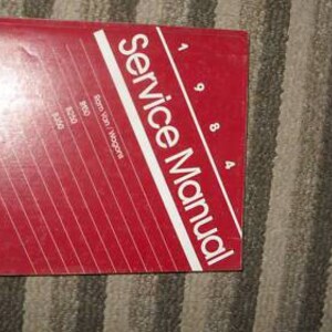 May include: A red Chrysler service manual for 1984 Ram Van/Wagons with the model numbers 1500, 2500, and 3500.