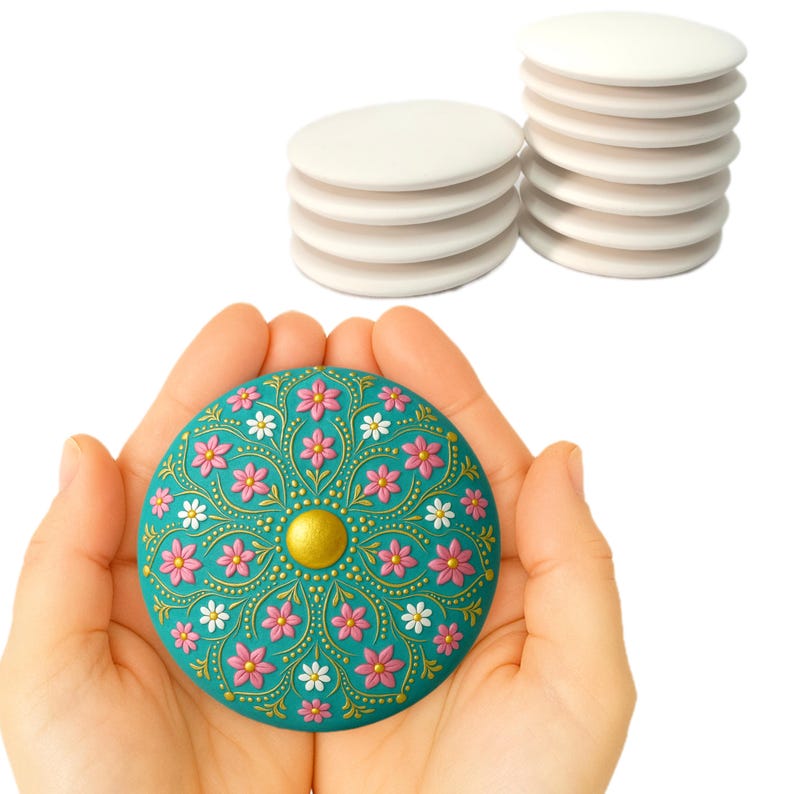 May include: A teal blue round trinket box with a gold center and pink and white floral design. The box is being held in a person's hands.