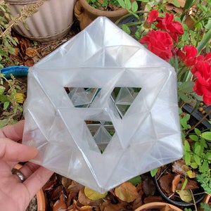 Pode incluir: Uma escultura geométrica de plástico transparente com um design triangular. A escultura é feita de muitos triângulos pequenos que estão conectados uns aos outros para formar um triângulo maior.