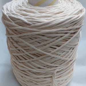Puede incluir: Un gran carrete de cuerda de algodón blanquecino. La cuerda está enrollada alrededor de un núcleo de cartón con rayas diagonales amarillas y blancas. Adecuado para macramé, manualidades u otros proyectos de bricolaje.