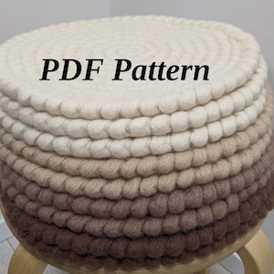 Puede incluir: Un otomán redondo y artesanal con una gradación de color, que va del crema al marrón. El texto "PDF Pattern" se muestra en la parte superior. El otomán está hecho de un material texturizado y en bucle.