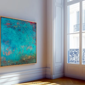 May include: Abstract teal and red artwork in a gold frame. The painting features a textured surface with a blend of teal, red, and brown hues. The artwork is displayed on a white wall in a room with a large window.