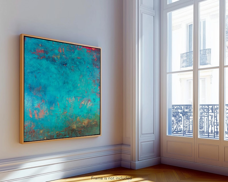 May include: Abstract teal and red artwork in a gold frame. The painting features a textured surface with a blend of teal, red, and brown hues. The artwork is displayed on a white wall in a room with a large window.