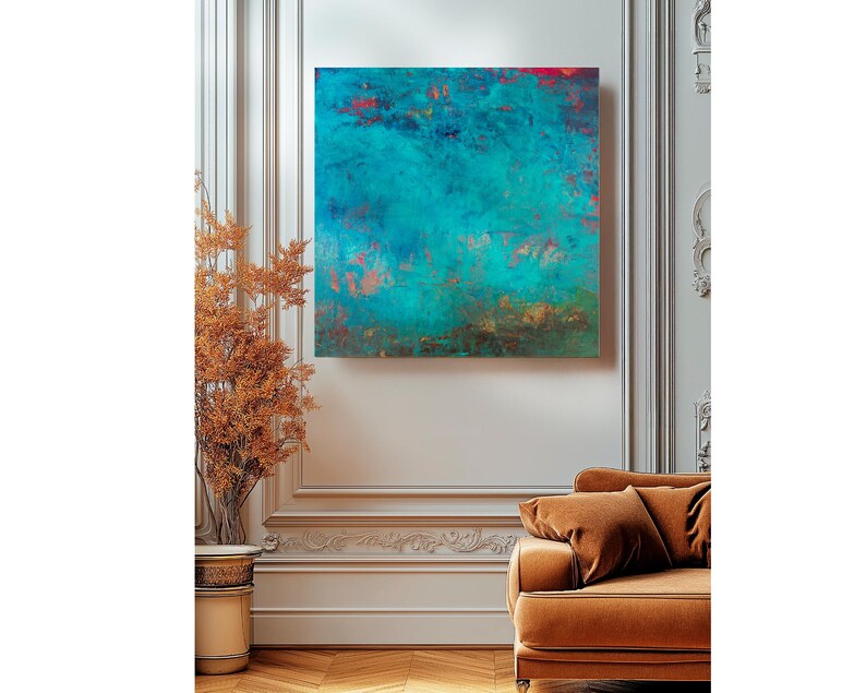 May include: An abstract square canvas art piece with a teal and turquoise colour palette, accented with red and copper tones. The artwork is mounted on a white wall above a brown sofa. A decorative plant in a gold pot is to the left.