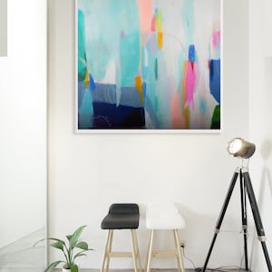 a painting hanging on a wall next to two stools