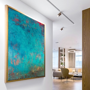 May include: Abstract artwork in a gold frame, featuring a teal and red colour scheme. The painting hangs on a white wall, adding a splash of colour to a modern interior. The textured surface and colour variations create a dynamic visual effect.