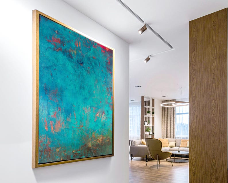 May include: Abstract artwork in a gold frame, featuring a teal and red colour scheme. The painting hangs on a white wall, adding a splash of colour to a modern interior. The textured surface and colour variations create a dynamic visual effect.