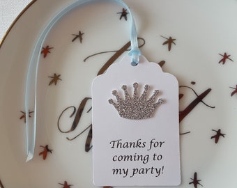 May include: A white gift tag with a silver glitter crown and the text "Thanks for coming to my party!" on a blue ribbon.