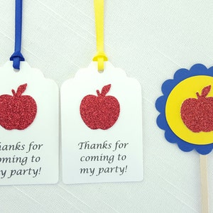 May include: Two white gift tags with red glitter apple designs and the text "Thanks for coming to my party!"  A blue and yellow cupcake topper with a red glitter apple design.