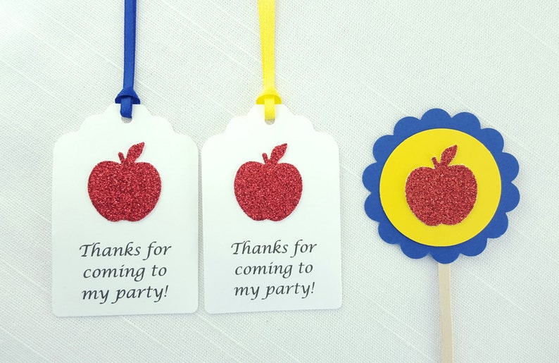May include: Two white gift tags with red glitter apple designs and the text "Thanks for coming to my party!"  A blue and yellow cupcake topper with a red glitter apple design.
