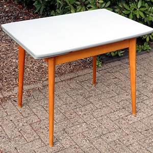 May include: A rectangular table featuring a smooth, light gray top surface with rounded corners and four tapered, light brown wooden legs. The table frame is constructed from matching light brown wood, providing a stable base for the tabletop.