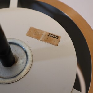 May include: Close-up of a white ceiling light fixture with a black cord and a brown label that reads "DORIA".
