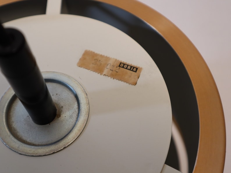May include: Close-up of a white ceiling light fixture with a black cord and a brown label that reads "DORIA".