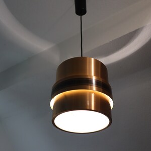 May include: A gold-toned pendant light with a white frosted glass shade. The light has a black cord and a black ceiling mount.