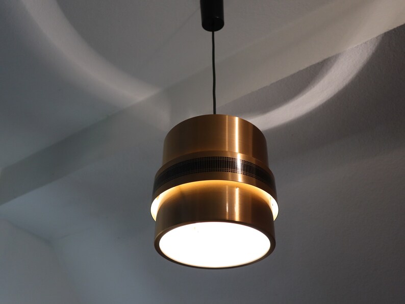 May include: A gold-toned pendant light with a white frosted glass shade. The light has a black cord and a black ceiling mount.