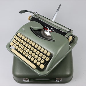 May include: A green typewriter with a cream-coloured keyboard and a silver carriage return lever. The typewriter is in a matching green case.
