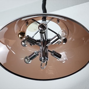 May include: A chrome and brown glass ceiling light fixture with five light bulbs. The fixture has a circular, saucer-shaped shade.