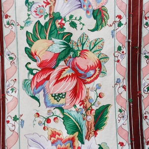 May include: A white fabric with a repeating pattern of pink, red, and green floral designs. The fabric has a burgundy stripe down the center.