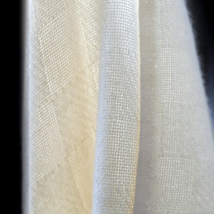 May include: Close-up of a white fabric with a textured weave. The fabric is folded in half, creating a smooth, even surface.