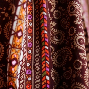 Puede incluir: Primer plano de una tela marr&oacute;n con un patr&oacute;n de paisley. La tela tiene un borde blanco, naranja y verde con un dise&ntilde;o geom&eacute;trico.