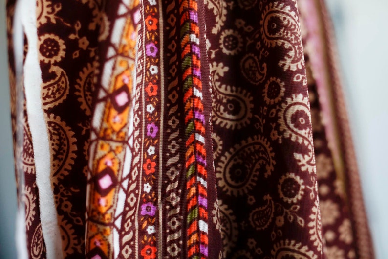 Puede incluir: Primer plano de una tela marr&oacute;n con un patr&oacute;n de paisley. La tela tiene un borde blanco, naranja y verde con un dise&ntilde;o geom&eacute;trico.