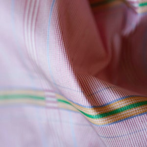May include: Pink and white checkered fabric with thin red stripes and a thicker green, yellow, and blue stripe.