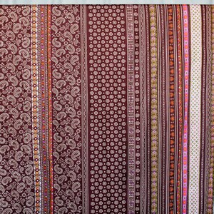 Puede incluir: Una tela marr&oacute;n con un patr&oacute;n repetitivo de paisley, flores y formas geom&eacute;tricas. La tela tiene un dise&ntilde;o de rayas verticales con diferentes colores, incluyendo blanco, naranja, rosa y verde.