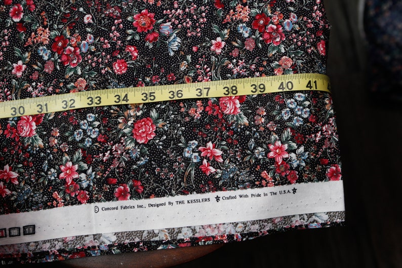 Pu&ograve; includere: Tessuto nero con stampa floreale in tonalit&agrave; di rosso, rosa, blu e verde. Il tessuto &egrave; misurato con un metro a nastro giallo che indica da 30 a 41 pollici. L'etichetta del tessuto recita "Concord Fabrics Inc., Designed By THE KESSLERS Crafted With Pride In The U.S.A."