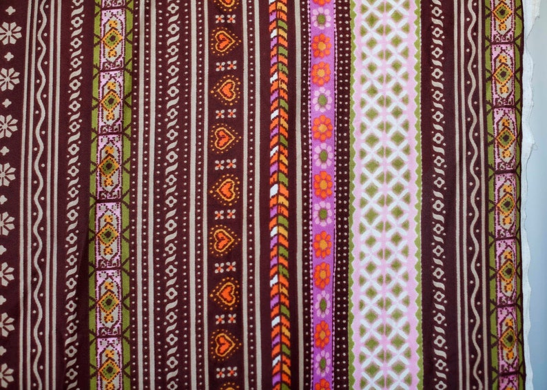 Puede incluir: Una tela marr&oacute;n con un patr&oacute;n repetitivo de rayas de colores y dise&ntilde;os geom&eacute;tricos. La tela presenta una variedad de colores, incluyendo naranja, rosa, verde y blanco.