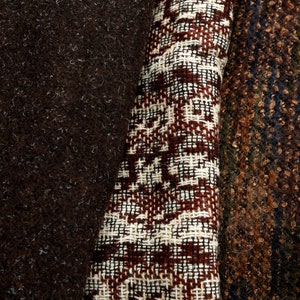 Może przedstawiać: Zbliżenie na brązową tkaninę z białym wzorem na brązowym tle. Tkanina ma fakturę tkanej i geometryczny wzór.