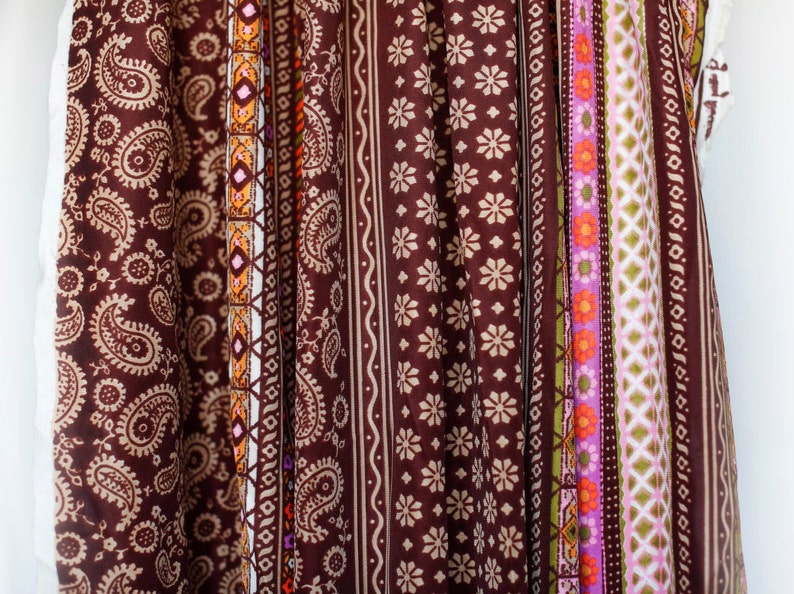 Puede incluir: Primer plano de una tela marr&oacute;n con una variedad de patrones coloridos. La tela presenta dise&ntilde;os de paisley, geom&eacute;tricos y florales.