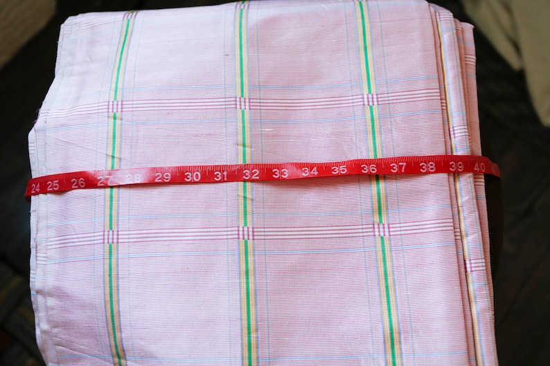 May include: Pink and white checkered fabric with a red measuring tape across it. The tape reads 24 to 40 inches.