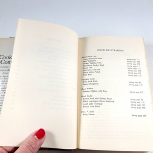 May include: Open cookbook with a list of color illustrations, including recipes like Texas Barbecued Duck and Strawberry Soda Pie. The book's cover is visible on the left, with the title "Cook Complete".
